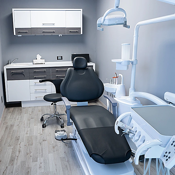 Consultorio de Denxal: sillón dental negro, unidad blanca y muebles grises, todo en orden