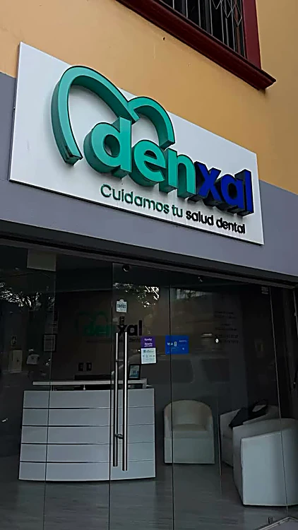 Fachada de Denxal en La Quemada 50 con el letrero iluminado “Cuidamos tu salud dental”